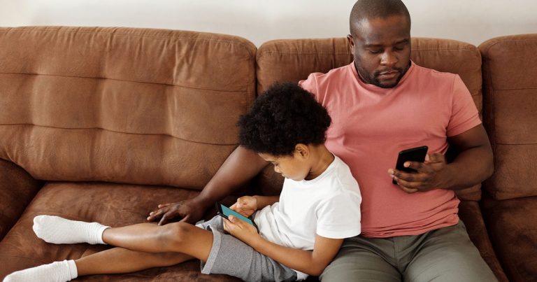Father-and-son-bonding-over-smartphones-while-relaxing-on-a-comfortable-couch-at-home